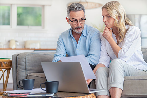 Happy mature couple using a laptop computer and doing paperwork on the sofa